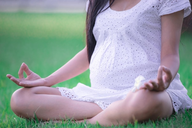 Retrato de una joven embarazada que juega yoga en el parque. Gente de Tailandia
