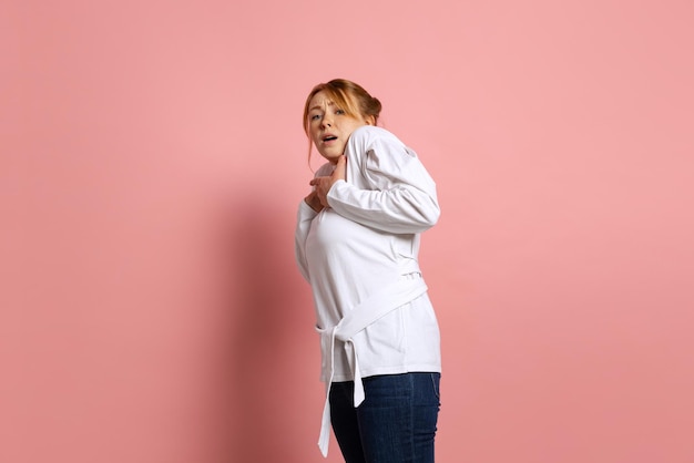 Retrato de una joven emotiva con una expresión de asombro posando aislada sobre un fondo rosa