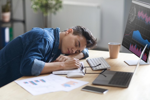 Retrato de un joven empleado cansado durmiendo en el trabajo