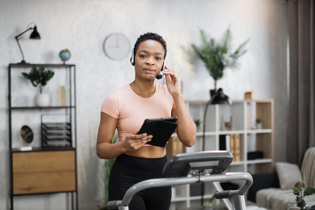 Retrato de una joven empresaria activa y dinámica con auriculares y tabletas haciendo deporte