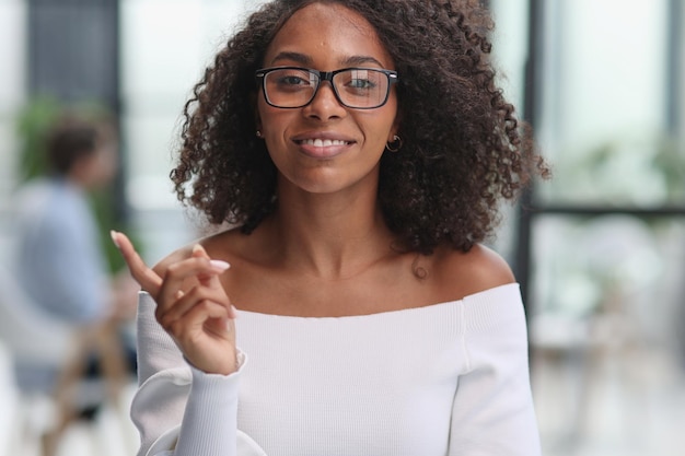 Retrato de una joven empresaria afroamericana que muestra un gesto con el dedo hacia un lado