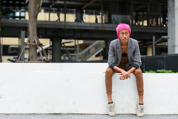 Retrato de joven empresaria asiática rebelde con cabello rosado en las calles de la ciudad al aire libre