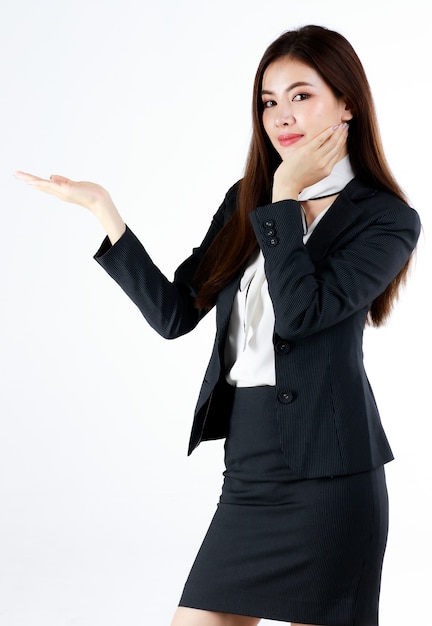 Retrato de joven empresaria asiática en traje formal posando y mostrando la mano en el espacio en blanco