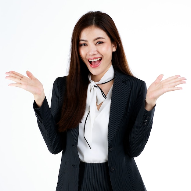 Retrato de joven empresaria asiática en traje formal posando y señalando con el dedo al espacio en blanco para presentar o demostrar bienes o productos en gesto publicitario, estudio de disparo sobre fondo blanco.