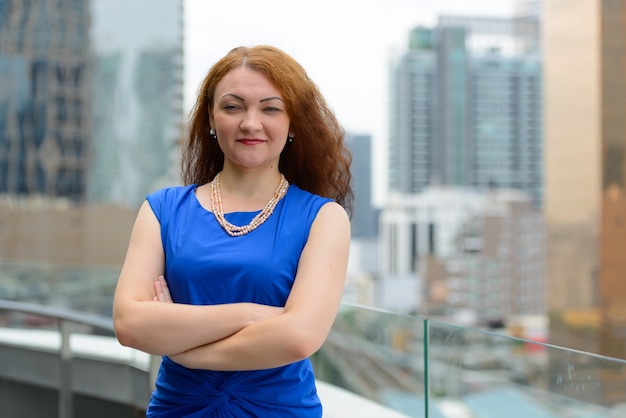 Retrato de joven empresaria con cabello rojo en la ciudad