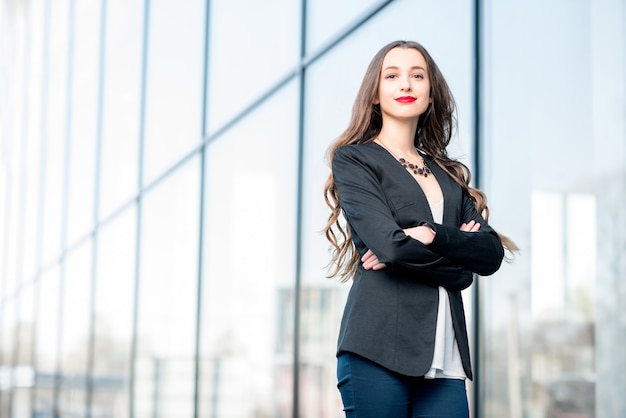 Retrato de una joven empresaria caucásica de pie al aire libre cerca de la fachada moderna