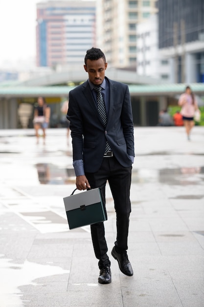 Retrato de joven empresario africano en las calles de la ciudad al aire libre