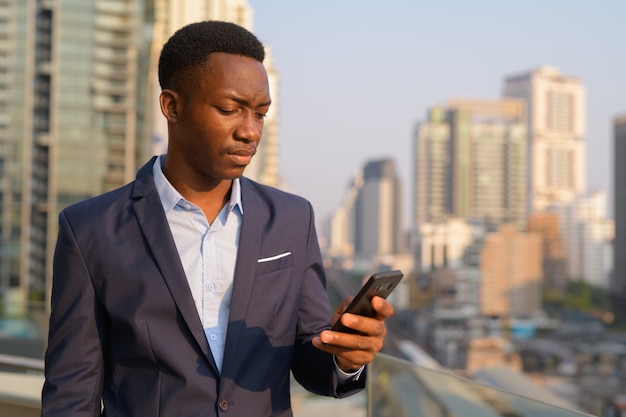 Retrato de joven empresario africano guapo contra la vista de la ciudad