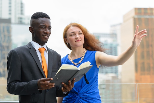 Retrato de joven empresario africano y joven empresaria con pelo rojo juntos