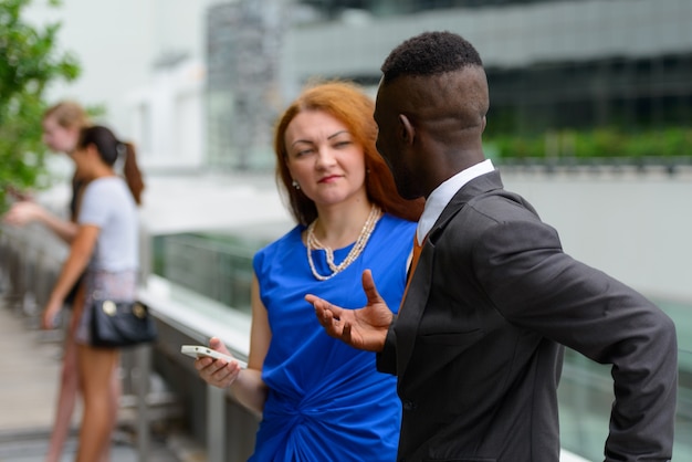 Retrato de joven empresario africano y joven empresaria con pelo rojo juntos