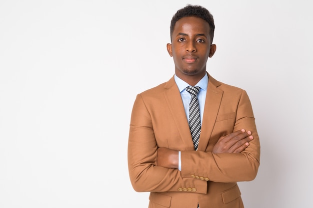 Retrato de joven empresario africano con pelo afro en traje marrón contra la pared blanca