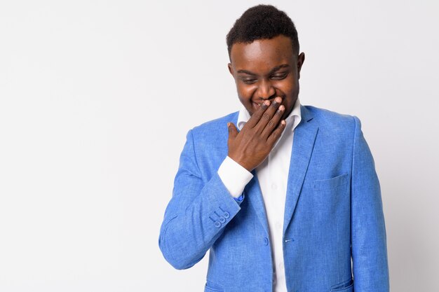 Retrato de joven empresario africano vistiendo traje azul contra la pared blanca