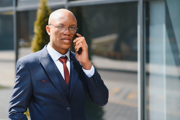 Retrato de un joven empresario afroamericano hablando por teléfono celular mientras está al aire libre en la ciudad