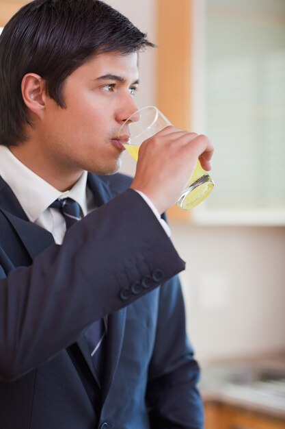 Retrato de un joven empresario bebiendo jugo de naranja en su cocina