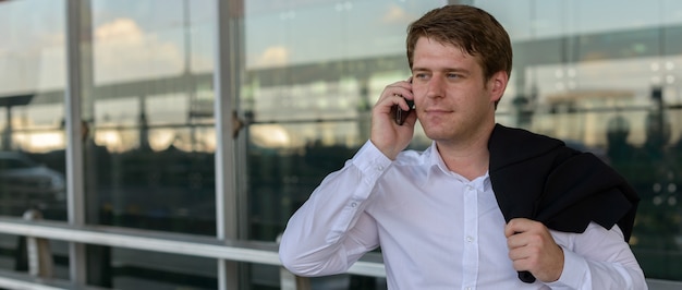 Retrato de joven empresario escandinavo guapo en el aeropuerto de la ciudad