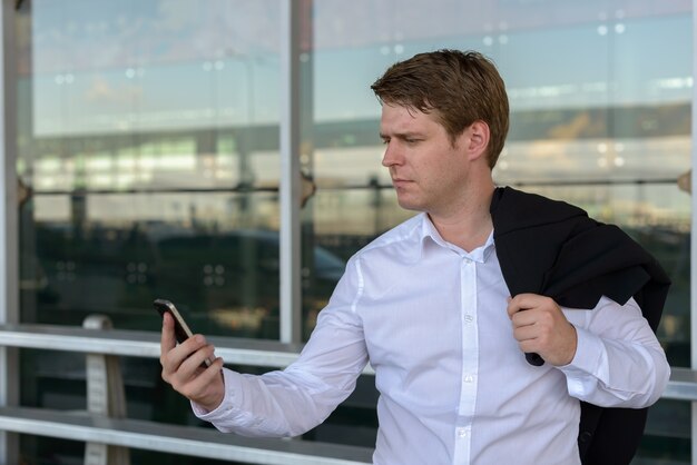 Retrato de joven empresario escandinavo guapo en el aeropuerto de la ciudad