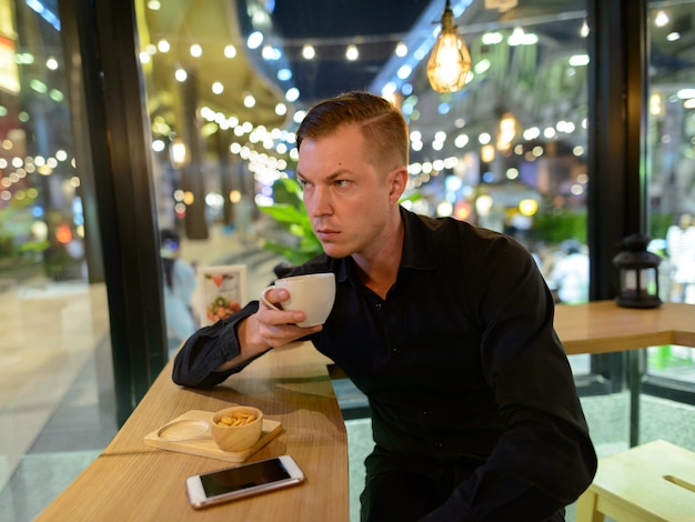 Retrato de joven empresario escandinavo guapo relajándose en la cafetería.