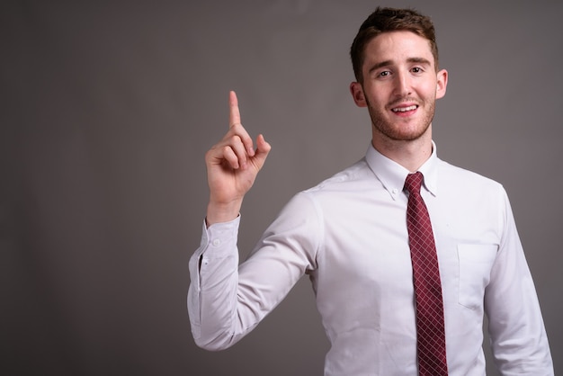 Retrato de joven empresario guapo contra gris