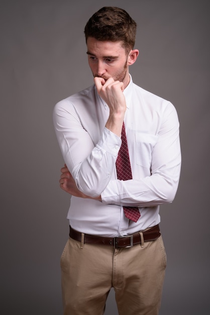 Retrato de joven empresario guapo contra gris