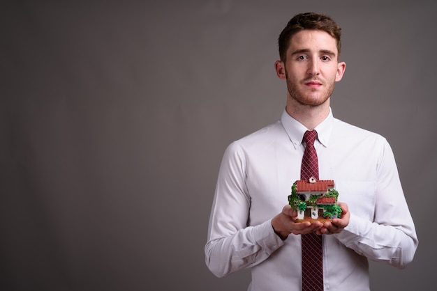 Retrato de joven empresario guapo contra gris