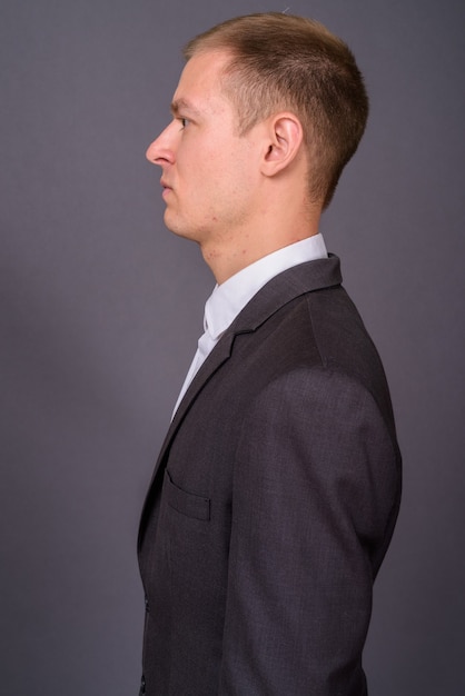 Retrato de joven empresario guapo contra la pared gris