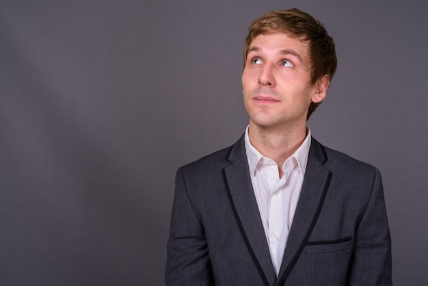 Retrato de joven empresario guapo contra la pared gris