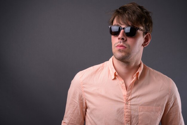 Retrato de joven empresario guapo contra la pared gris