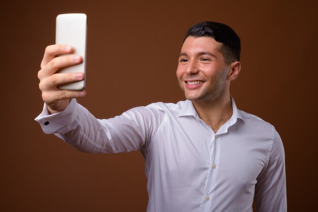 Retrato de joven empresario guapo contra la pared marrón