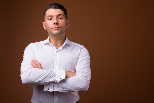 Retrato de joven empresario guapo contra la pared marrón