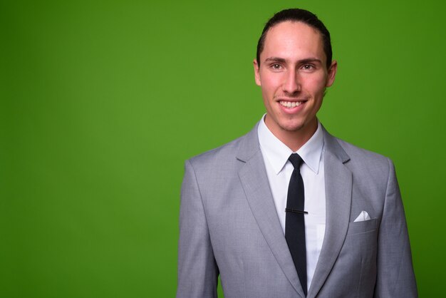 Retrato de joven empresario guapo contra la pared verde