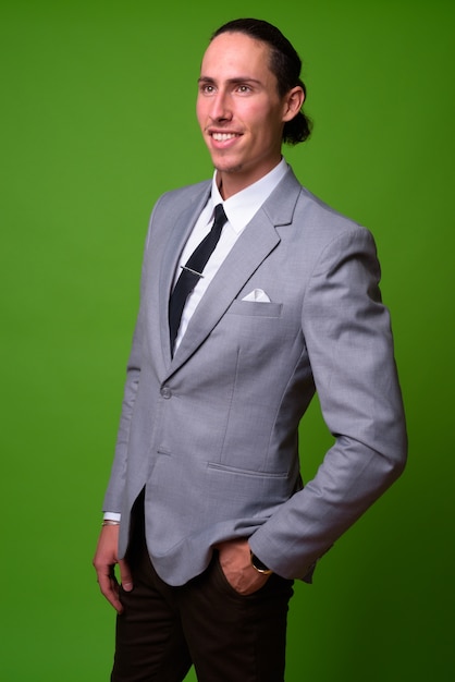 Retrato de joven empresario guapo contra la pared verde