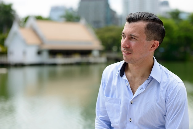 Retrato de joven empresario guapo contra la vista del lago en el parque