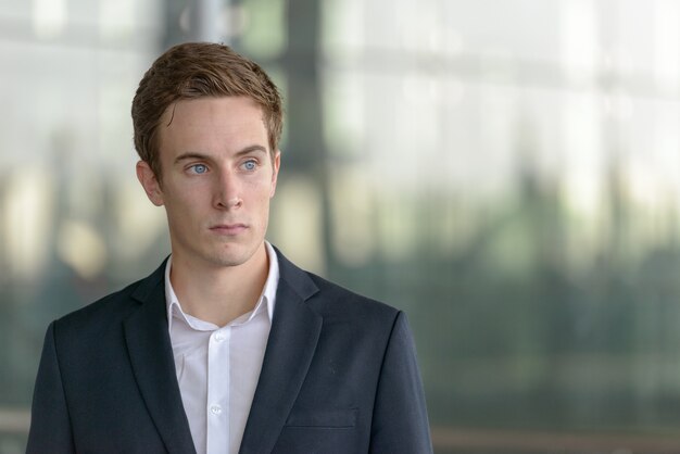 Retrato de joven empresario guapo en traje en el aeropuerto al aire libre