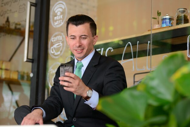 Retrato de joven empresario guapo en traje en la cafetería al aire libre