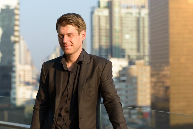 Retrato de joven empresario guapo en traje contra la vista de la ciudad