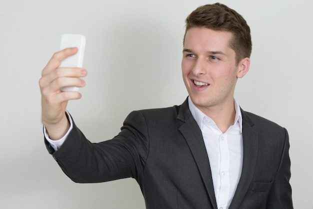 Retrato de joven empresario guapo vistiendo traje contra la pared blanca