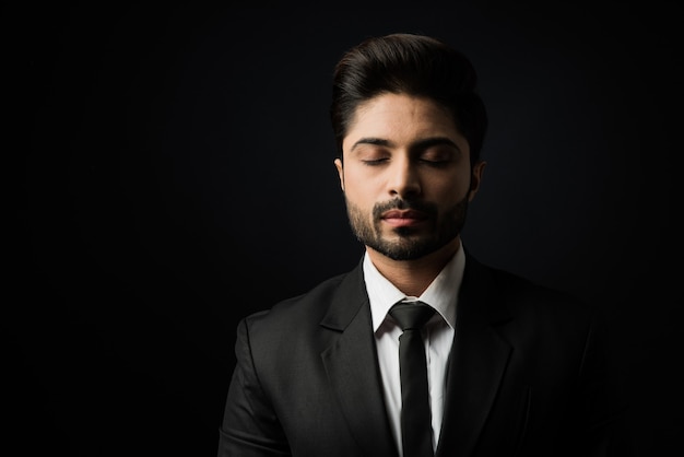 Retrato de joven empresario indio barbudo contra fondo negro, iluminación cambiante