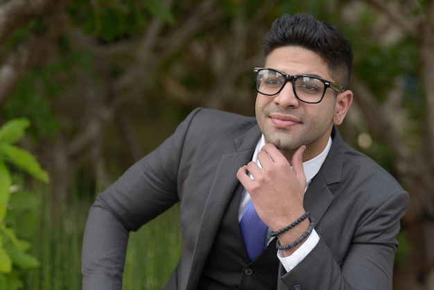 Retrato de joven empresario indio guapo relajándose en el parque al aire libre