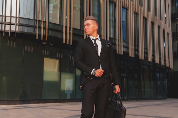 Retrato joven empresario con maletín sobre la construcción de la empresa corporativa, mirando a otro lado, estilo de vida