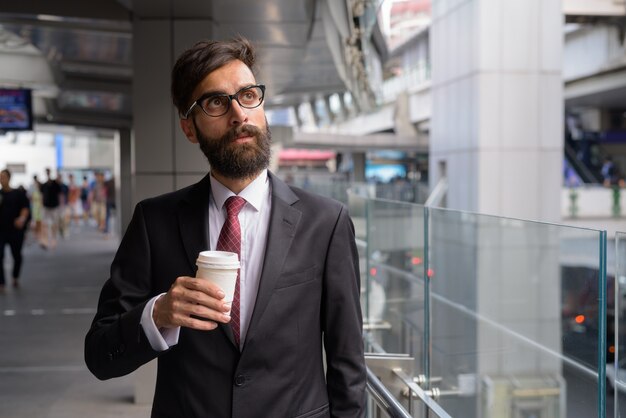 Retrato de joven empresario persa barbudo guapo relajándose en la ciudad de Bangkok