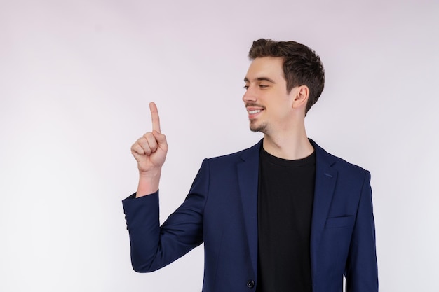 Foto retrato de joven empresario señalando con el dedo el espacio de copia aislado sobre fondo blanco de estudio