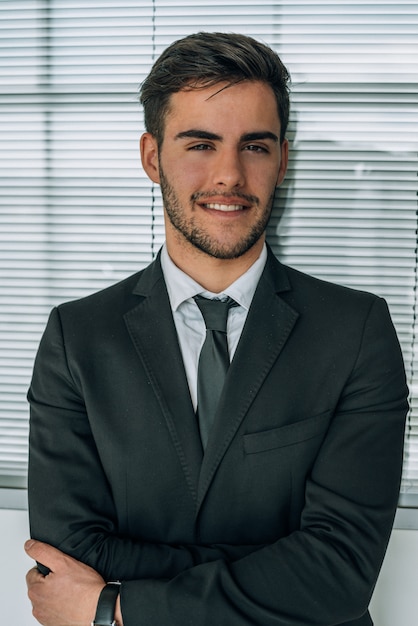 Retrato de joven empresario sonriendo en el aeropuerto con traje