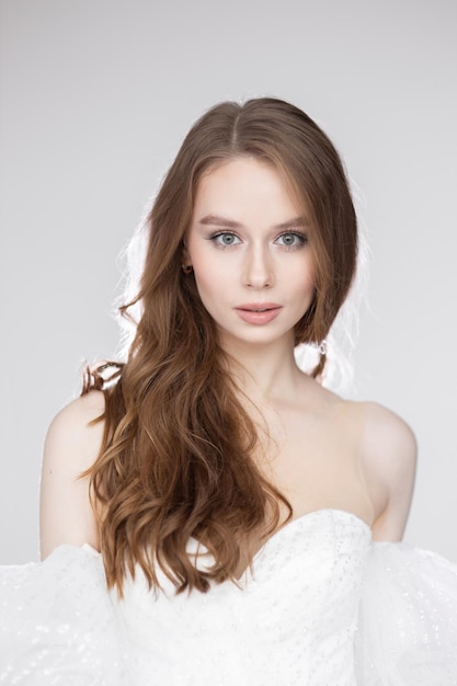 Retrato de una joven encantadora con un lujoso vestido blanco sobre un fondo negro. Una novia con un vestido de novia, una sonrisa feliz y un retrato.