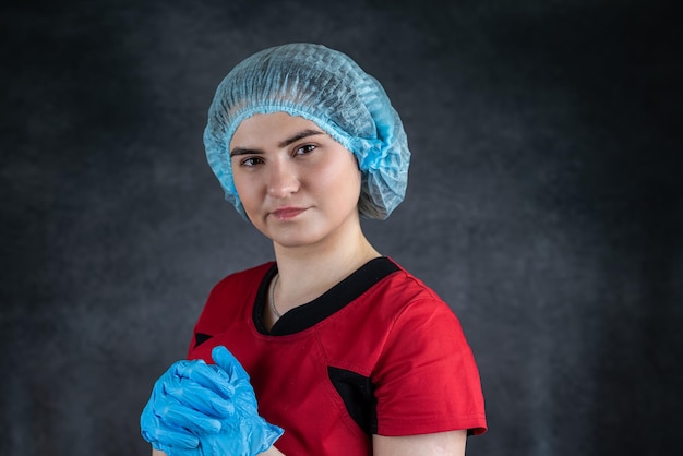 Retrato de una joven enfermera o doctora caucásica que usa guantes azules uniformes rojos con estetoscopio Concepto médico