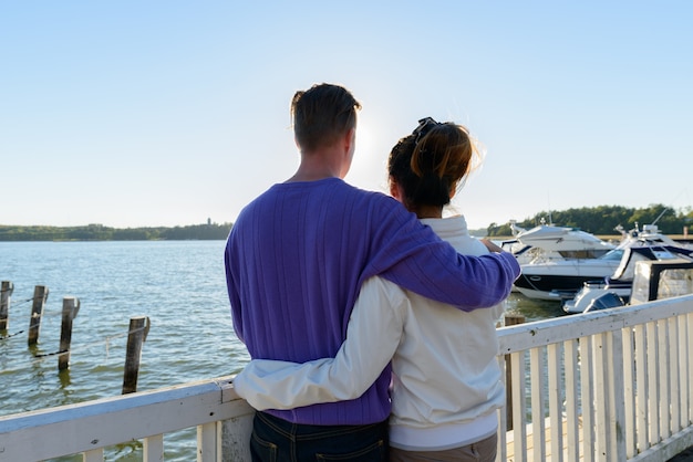 Retrato de joven escandinavo y joven asiática como pareja multiétnica juntos y enamorados en el muelle al aire libre