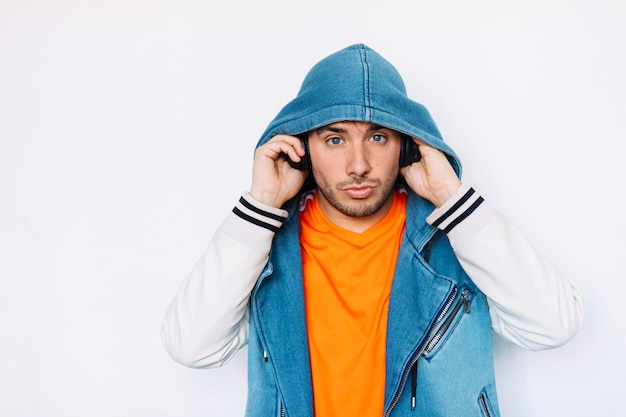 Retrato de un joven escuchando música mientras está de pie contra un fondo blanco