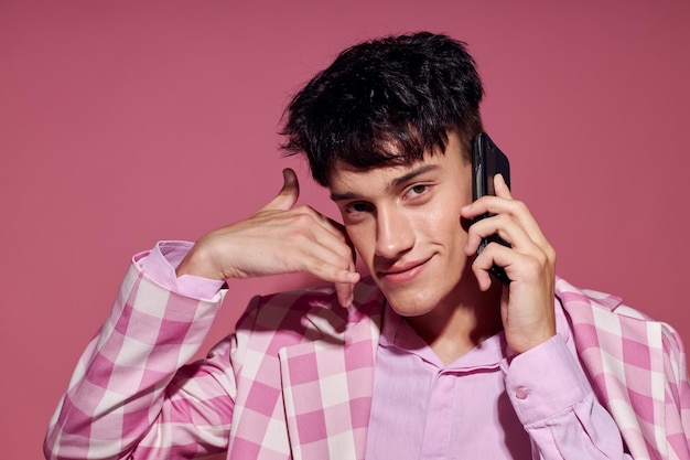 Retrato de un joven de estilo moderno de la moda de la chaqueta a cuadros que habla en el estudio del modelo del teléfono