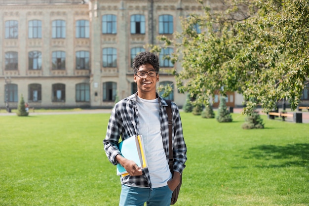 Retrato de un joven estudiante afroamericano hombre negro el fondo de la universidad.