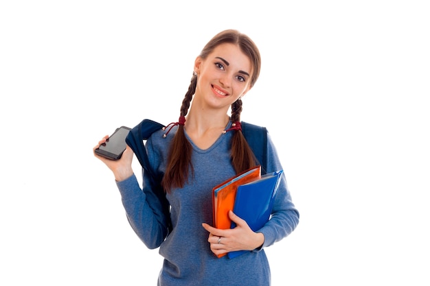 Retrato de joven estudiante atractiva con mochila y cuadernos aislado sobre fondo blanco.