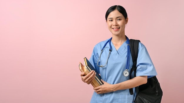 Retrato de una joven estudiante de medicina sonriendo a la cámara mientras sostenía libros de texto